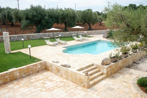 a swimming pool in a yard with chairs at Quattroperle Trulli - Relax - Puglia in Castellana Grotte