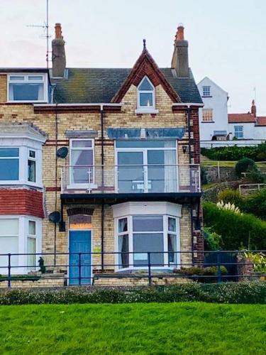 a brick house with blue doors on a grass field at Coble House Filey in Filey
