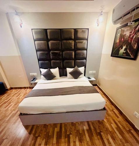 a bedroom with a large bed with a large headboard at Hotel Airport City in New Delhi