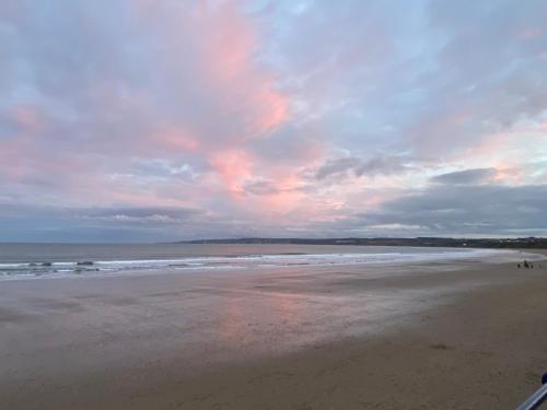 a beach with a cloudy sky and the ocean at Coble House Filey in Filey