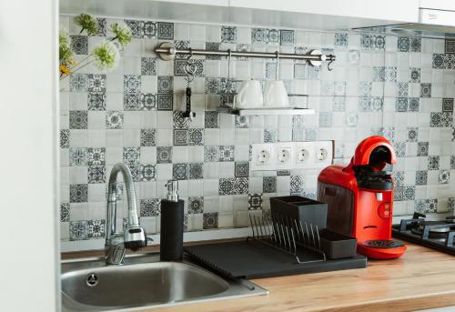 a kitchen with a sink and a red appliance on a counter at Garsonieră Centru Petroșani in Petroşani