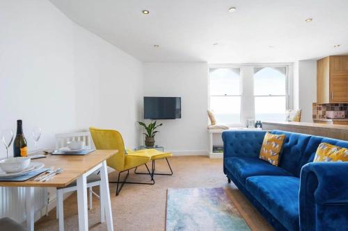 a living room with a blue couch and a table at Stylish Flat with Stunning Sea Views Ilfracombe in Ilfracombe