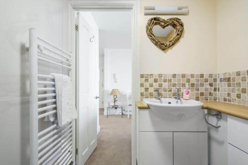 a bathroom with a sink and a heart plaque on the wall at Stylish Flat with Stunning Sea Views Ilfracombe in Ilfracombe