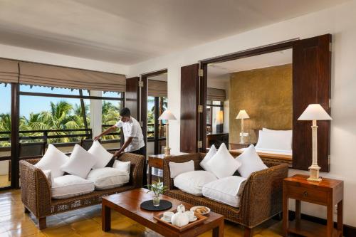 a man cleaning a living room with white furniture at Jetwing Beach in Negombo