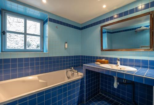 a blue tiled bathroom with a tub and a sink at Hostellerie de l'Écu de Bretagne in Beaugency