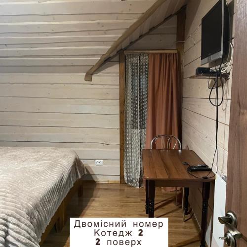 a bedroom with a bed and a desk and a television at Pidkova in Verkhovyna