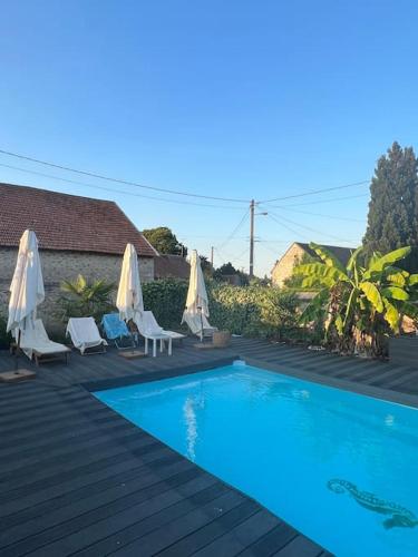 - une piscine avec des chaises et des parasols sur une terrasse dans l'établissement Maison de campagne avec piscine, à Soisy-Bouy