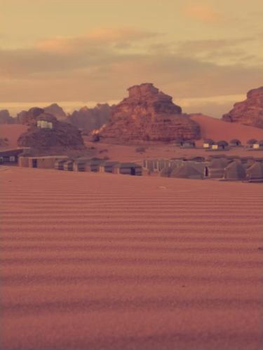 a view of a desert with mountains in the background at blueskyrum. in Wadi Rum