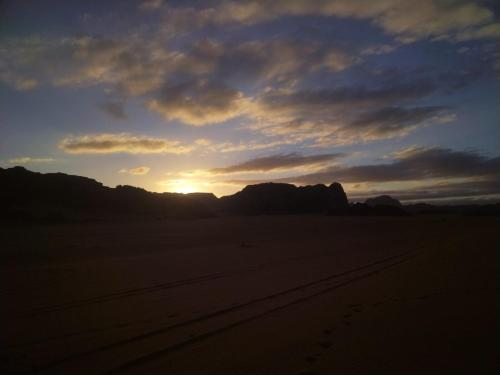 a sunset in the desert with mountains in the background at blueskyrum. in Wadi Rum