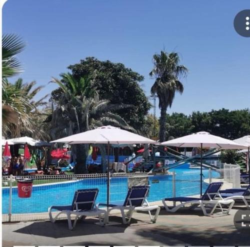 Grupa krzeseł i parasoli obok basenu w obiekcie Casa Emma w mieście Poblete