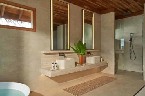 a bathroom with two sinks and a shower at Huvafen Fushi Maldives in North Male Atoll