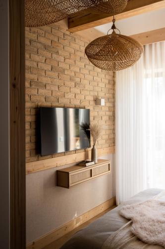 a bedroom with a tv on a brick wall at Villa La Roca Garden and Spa in Kościelisko