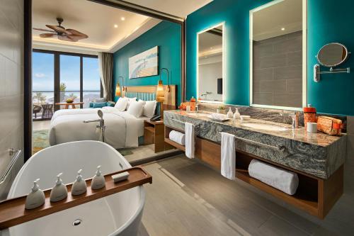a bathroom with a bed and a tub in a room at Angsana Quan Lan, Ha Long Bay in Quan Lạn