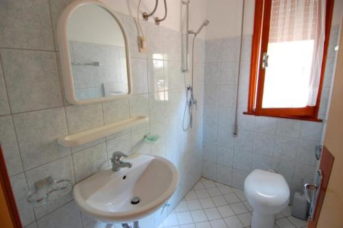 a bathroom with a sink and a mirror and a toilet at Cozy flat in Rosolina in Rosolina Mare