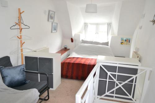 une petite chambre avec un lit et une chaise dans l'établissement Sailmaker's Cottage, à Shaldon