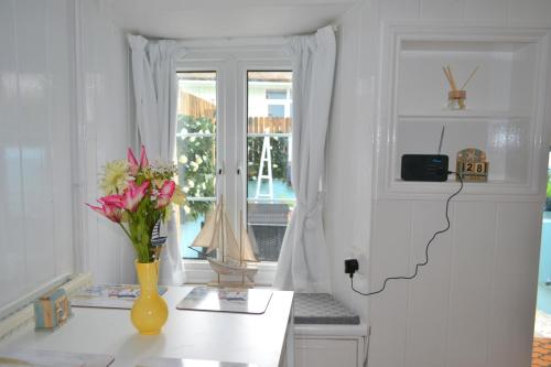 Chambre blanche avec un vase de fleurs sur une table dans l'établissement Sailmaker's Cottage, à Shaldon