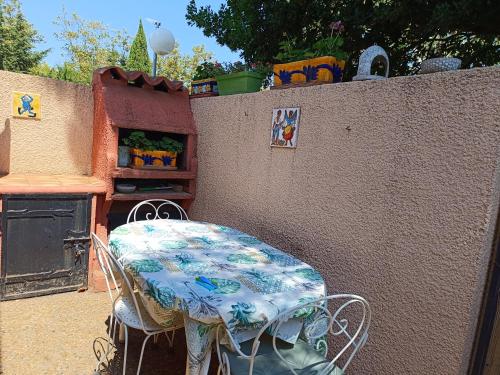 une table et des chaises assises à côté d'un mur dans l'établissement Pavillon de vacances proche plage et commerces avec parking - 4CAP31, à Saint Cyprien Plage