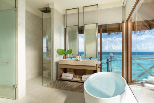 a bathroom with a tub and a view of the ocean at Huvafen Fushi Maldives in North Male Atoll