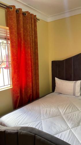 a bedroom with a bed and a window with curtains at Spacious City Home in Kampala