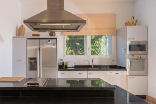 a kitchen with white cabinets and a stainless steel refrigerator at Villa Iris in Benalup Casas Viejas