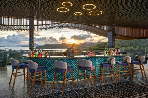 a bar with chairs and a man in the background at Angsana Quan Lan, Ha Long Bay in Quan Lạn