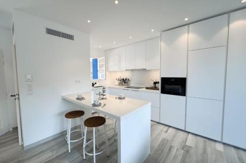 - une cuisine blanche avec des placards et des tabourets blancs dans l'établissement Charming House for Rent in Port Grimaud with Wi-Fi and Private Mooring, à Grimaud