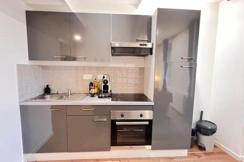 a small kitchen with a sink and a refrigerator at Cocon Coeur de Ville in Villefranche-de-Lauragais