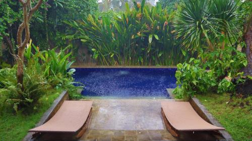 two benches sitting in front of a swimming pool at Pranajaya loka villa in Tejakula