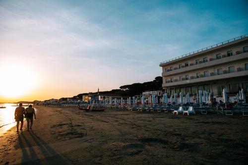 two people walking on the beach near a hotel at Hotel Parrini in Follonica