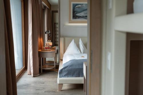 a bedroom with a bed and a table with a night stand at Hotel Piz St. Moritz in St. Moritz