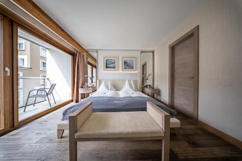 a bedroom with a bed and a large window at Hotel Piz St. Moritz in St. Moritz
