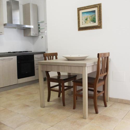 a kitchen with a wooden table and chairs at Villa Dei Lidi - HomeSalento com in Torre San Giovanni Ugento