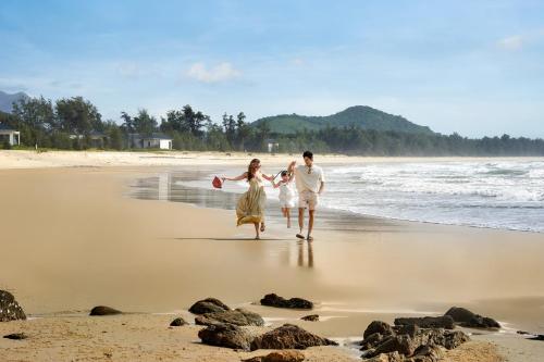 a man and a woman running on the beach at Angsana Quan Lan, Ha Long Bay in Quan Lạn