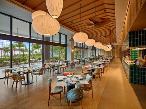 a restaurant with tables and chairs and large windows at Angsana Quan Lan, Ha Long Bay in Quan Lạn