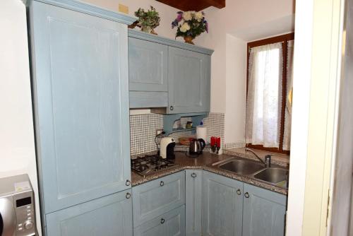 a kitchen with blue cabinets and a sink at CASA MAIRA IN CENTRO A SATURNIA in Saturnia