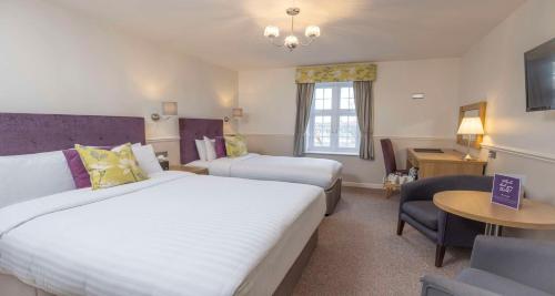 a hotel room with two beds and a table at Worcester Bank House Hotel Spa & Golf; BW Premier Collection in Worcester