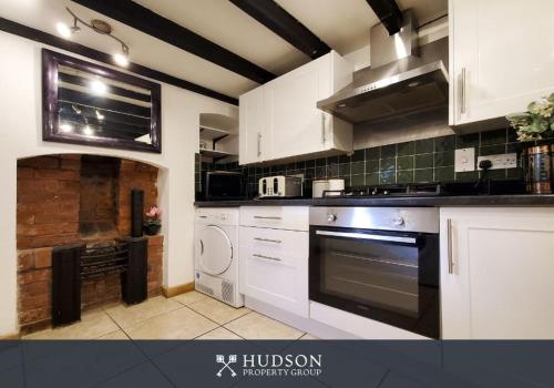a kitchen with white cabinets and a stove top oven at Town Centre Period Property by Shrewsbury Abbey in Shrewsbury