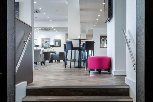 a corridor of an office with a pink chair at Garner Hotel Preston Samlesbury by IHG in Preston