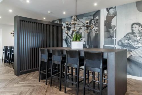 a dining room with a bar with black chairs at Garner Hotel Preston Samlesbury by IHG in Preston