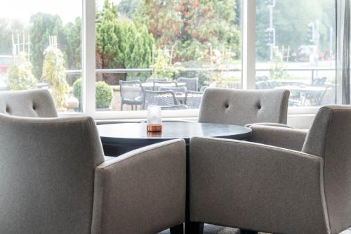 a table and chairs in a room with a large window at Garner Hotel Preston Samlesbury by IHG in Preston
