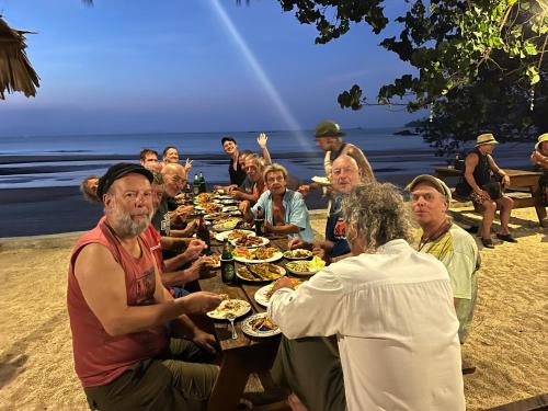 a group of people sitting around a table with food at Baanbua bungalows Koh Chang Ranong in Koh Chang Ranong