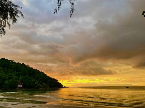 a sunset over a body of water with a cloudy sky at Baanbua bungalows Koh Chang Ranong in Koh Chang Ranong