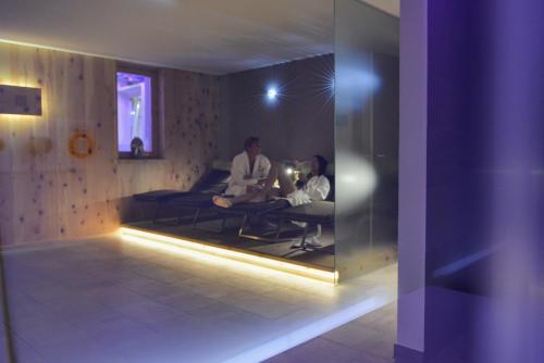 two people sitting in a room with a mirror at Mountainlodge Luxalpine in San Vigilio Di Marebbe