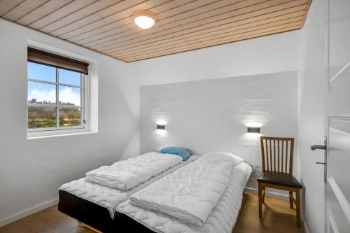 a bed in a room with a window and a chair at Large Holiday Home For 20 People With Large Pool, Hot Tub For 7 People And Activity Room in Ringkøbing