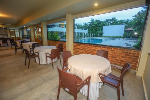 a restaurant with tables and chairs and a large window at Nilan Zingle Resort in Puducherry