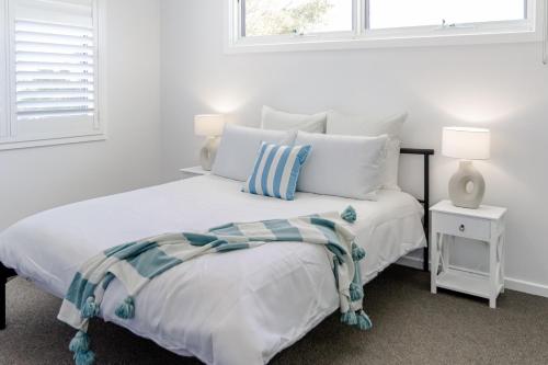 a white bedroom with a bed and a window at Coastal Dreams (#1) in Dromana
