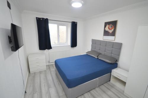 ein Schlafzimmer mit einem blauen Bett und einem Fenster in der Unterkunft Regent House in Seven Kings
