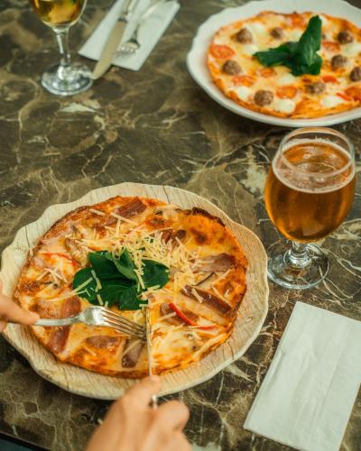 two pizzas on a table with a person eating a pizza at Sundia Exclusive By Liberty Fethiye Adults Only in Fethiye