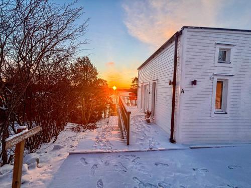 a building in the snow with the sunset in the background at New lakehouse - amazing sea view and private pier! in Stockholm