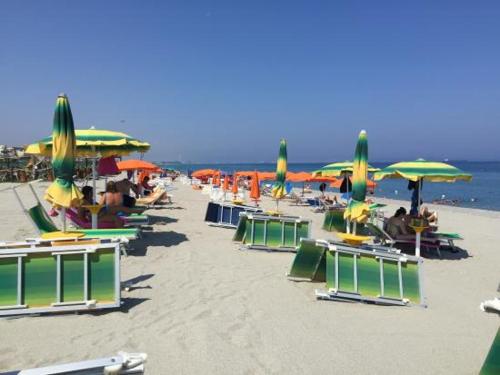 a group of chairs and umbrellas on a beach at La Baia Di Ulisse in Venetico